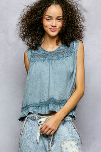 Woman wearing a denim sleeveless top and shorts against a gray background