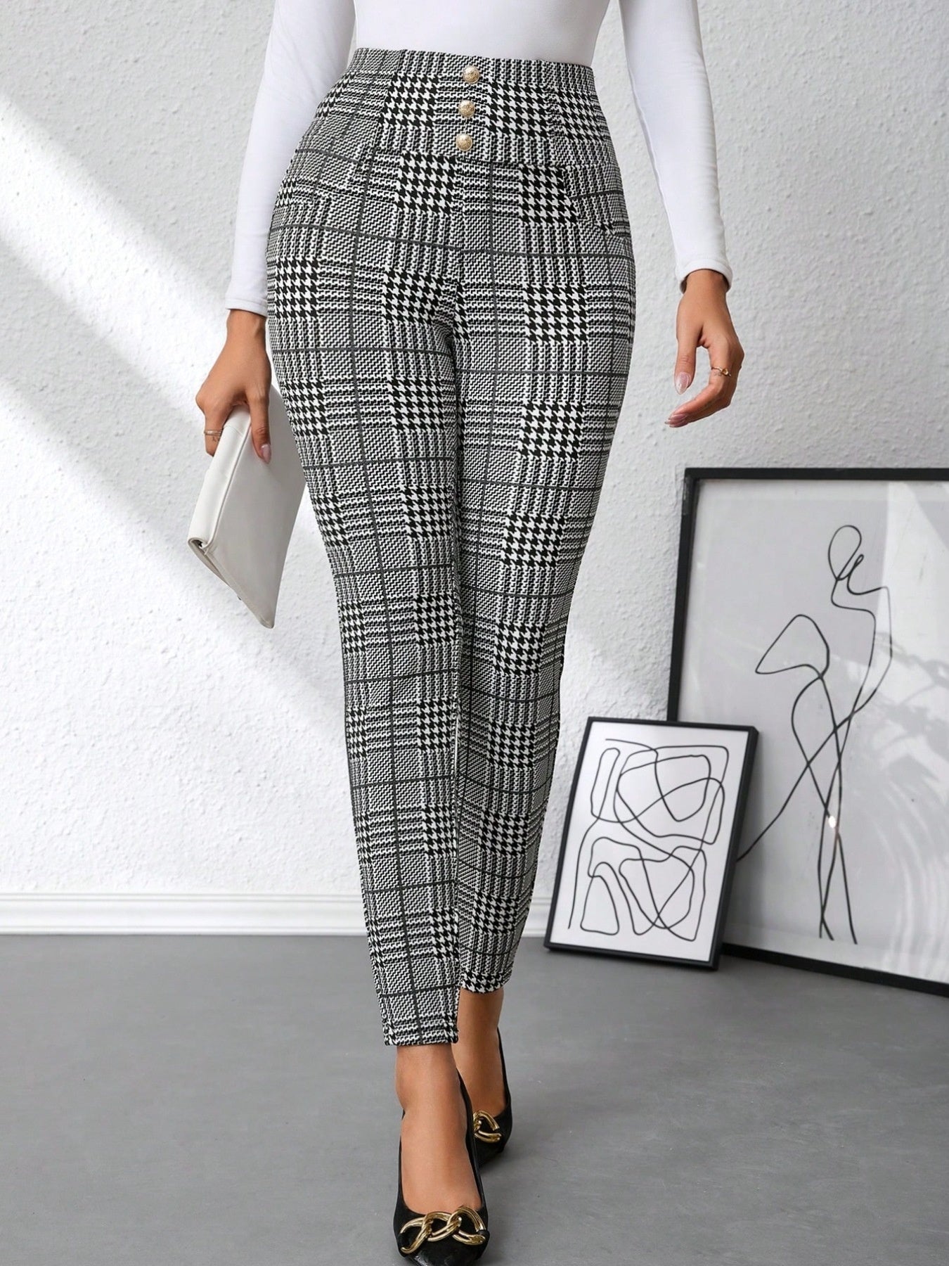 Person wearing black and white checkered pants in a minimalistic room.