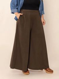 Person wearing brown wide-leg pants with a plain background