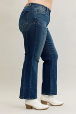 Person wearing blue jeans and white boots on a plain background
