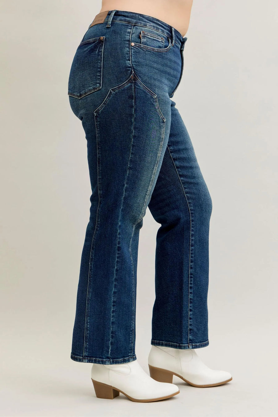 Person wearing blue jeans and white boots on a plain background