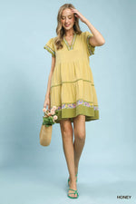 Woman wearing a yellow dress with floral details on a light blue background
