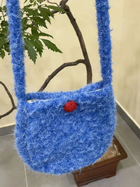 Blue textured handbag with a red button on a neutral background