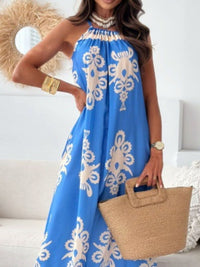 Woman wearing a blue dress with white patterns, holding a straw bag indoors.