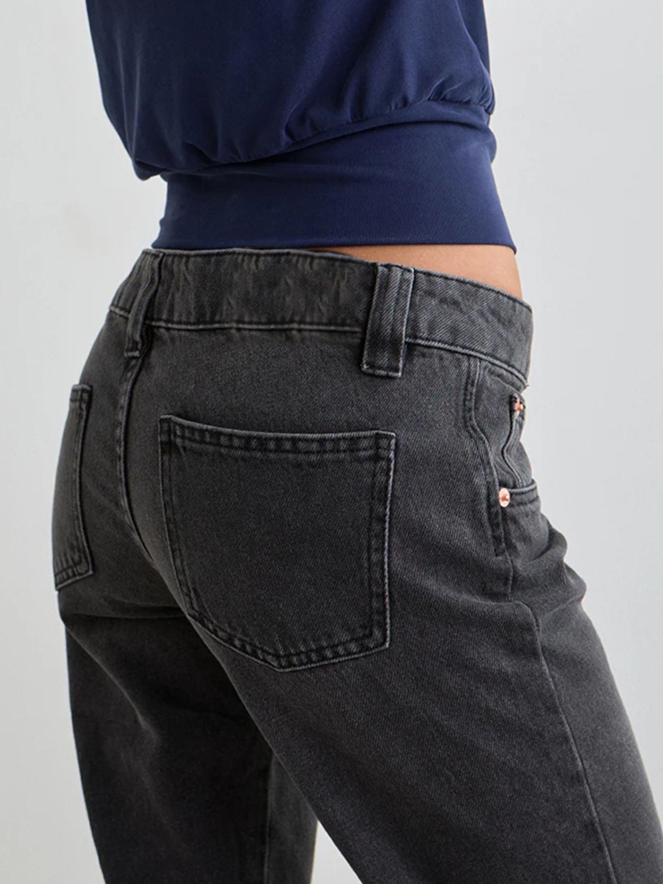 Person wearing black jeans and a navy top on a light gray background