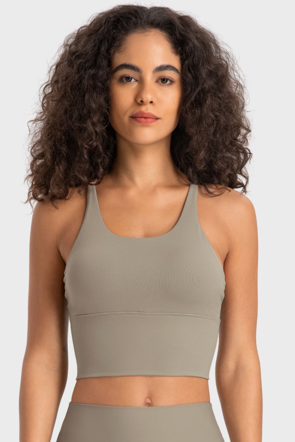 Woman wearing a green sports bra and leggings on a white background