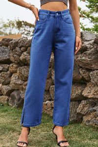 Person wearing blue jeans standing in front of a stone wall.