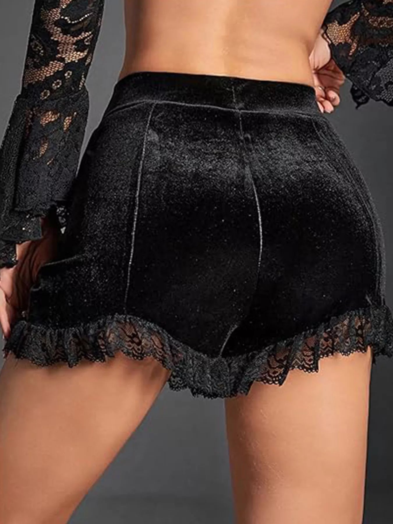 Black lace shorts worn by a person on a gray background
