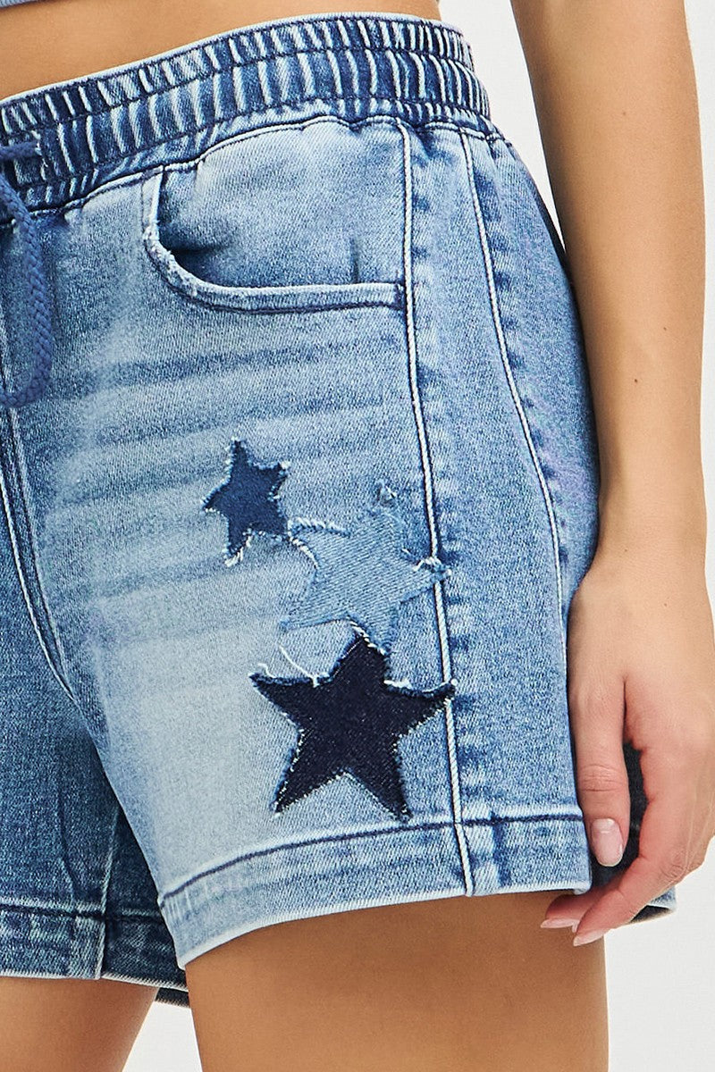Close-up of blue denim shorts with star patches on a white background