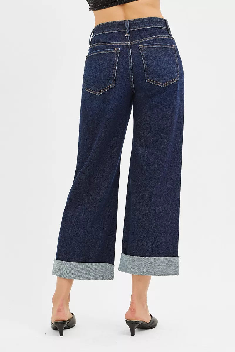 Dark blue wide-leg jeans worn by a person on a white background