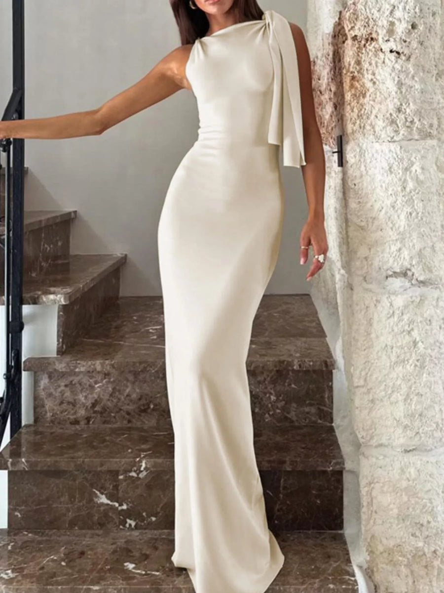 Woman in a white evening gown standing on a staircase.