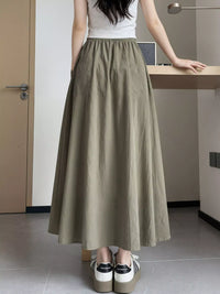 Person wearing a long olive green skirt in an indoor setting