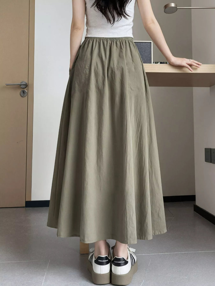 Person wearing a long olive green skirt in an indoor setting
