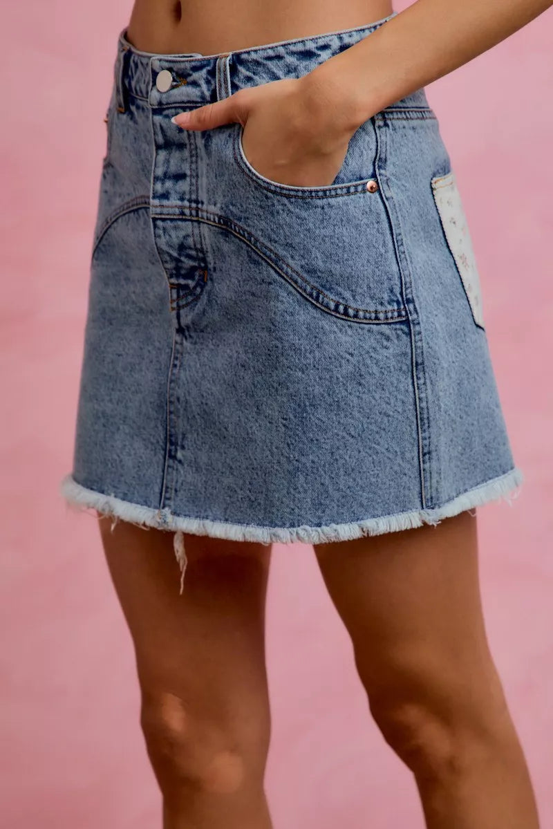 Blue denim skirt worn by a person on a pink background