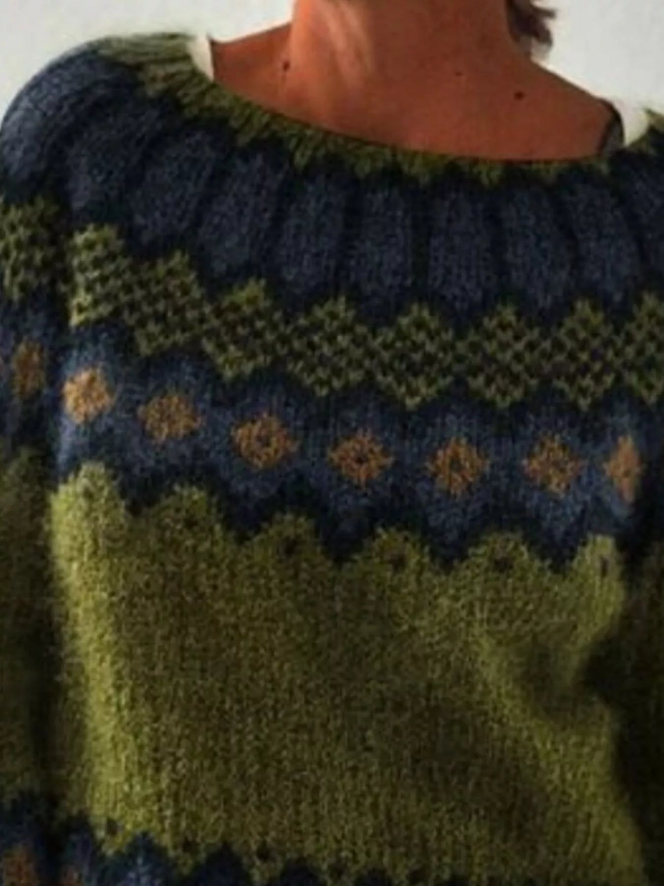 Close-up of a person wearing a patterned sweater with green and blue colors.