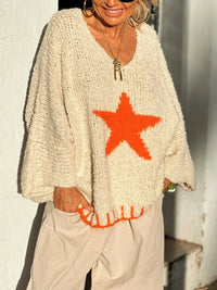 Person wearing a cream sweater with a red star design against a light background