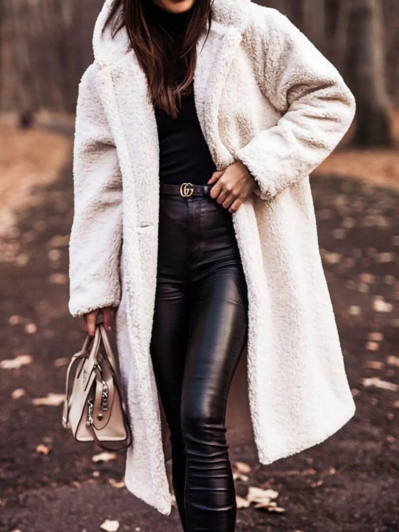 Person wearing a white fur coat and black leather pants outdoors.