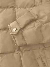 Close-up of a beige puffer jacket with a button detail