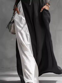 Person wearing a black and white outfit with a gray background
