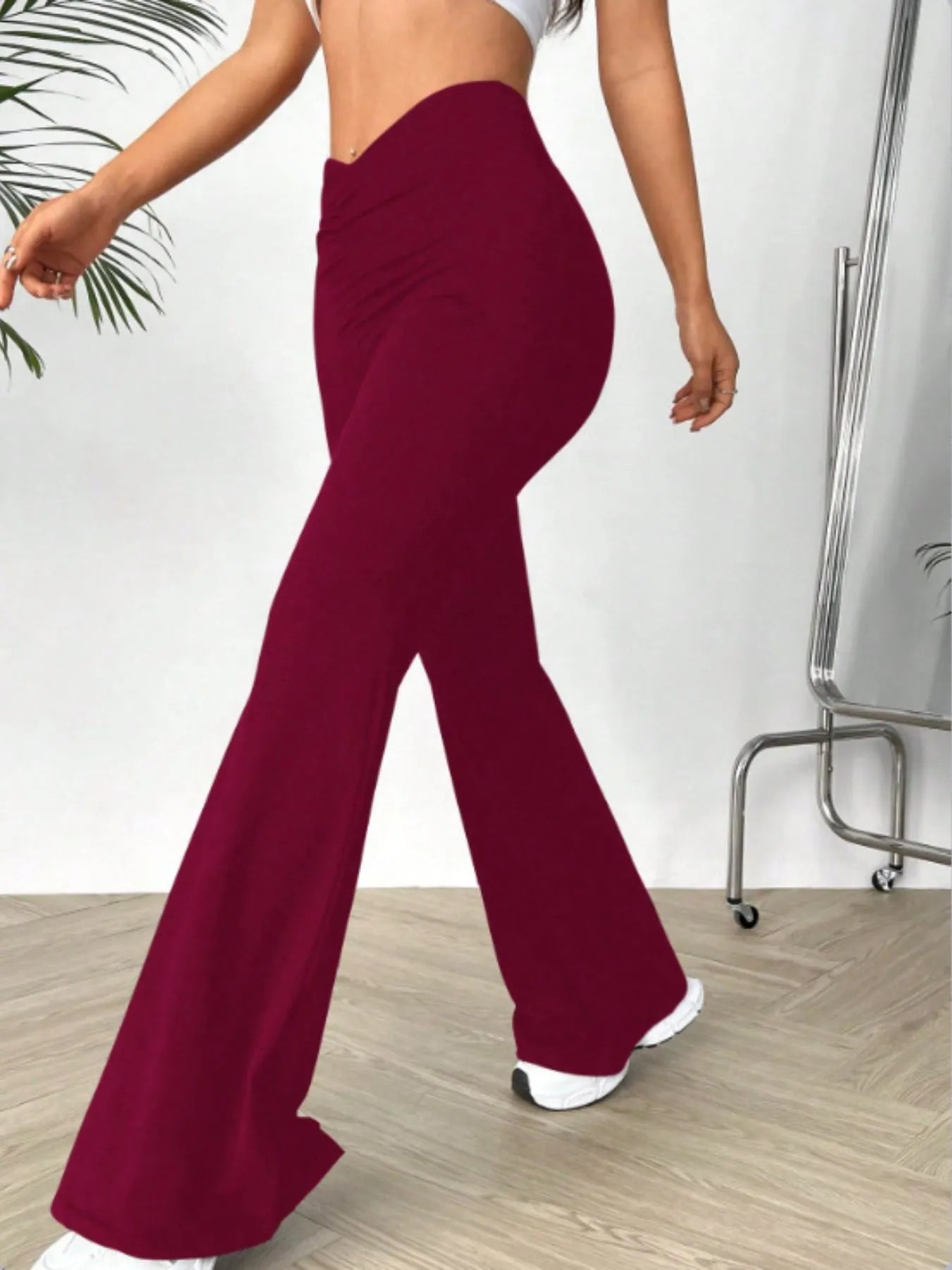 Person wearing burgundy flared pants in a minimal indoor setting