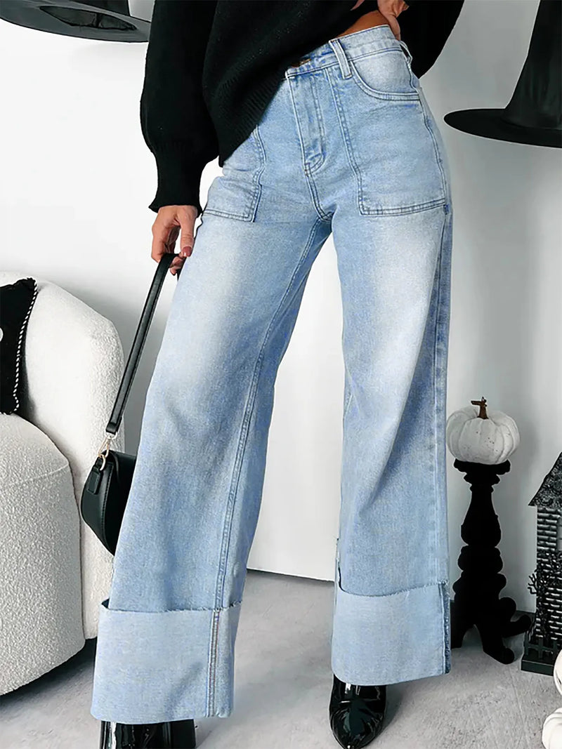 Person wearing light blue jeans in a room with a white wall and decorative items.