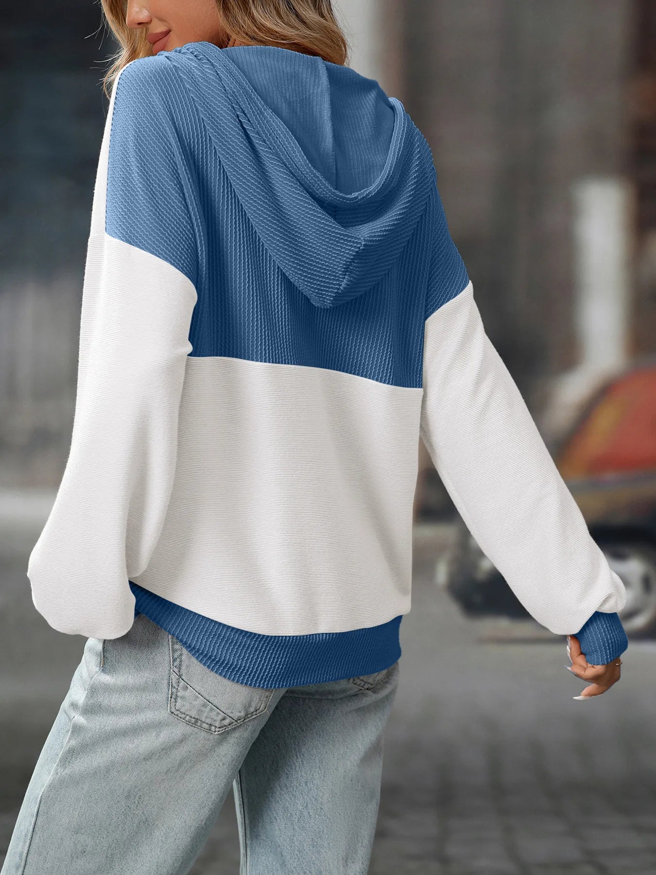 Person wearing a blue and white hoodie with a blurred background