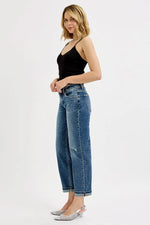 Woman wearing a black top and blue jeans on a white background