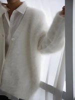 Person wearing a white shirt and light gray cardigan against a white background