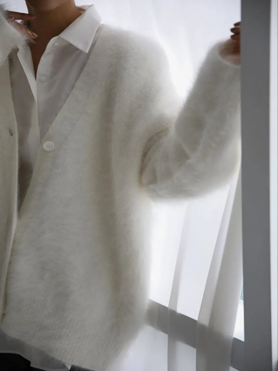Person wearing a white shirt and light gray cardigan against a white background