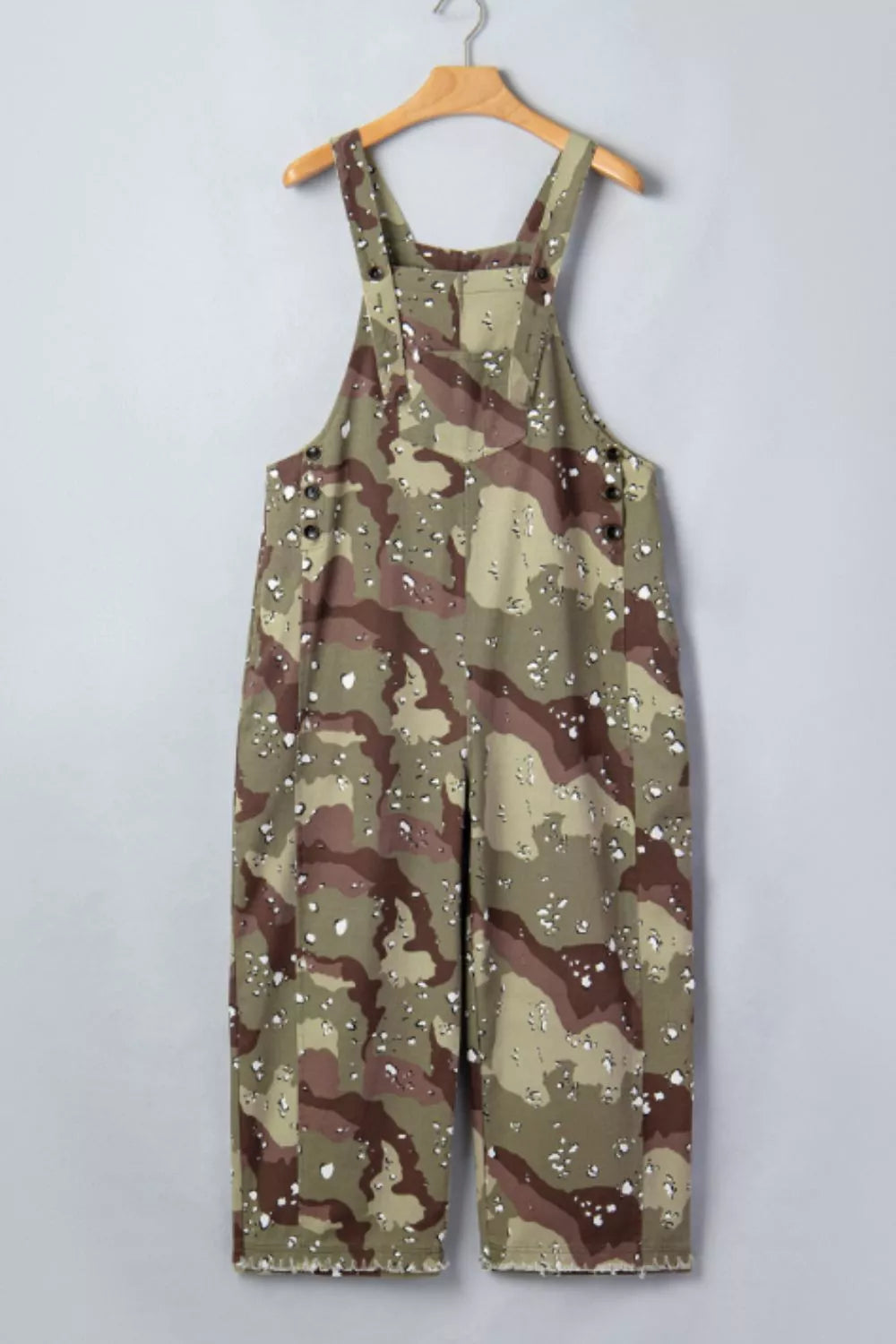 Camouflage overalls on a hanger against a plain background