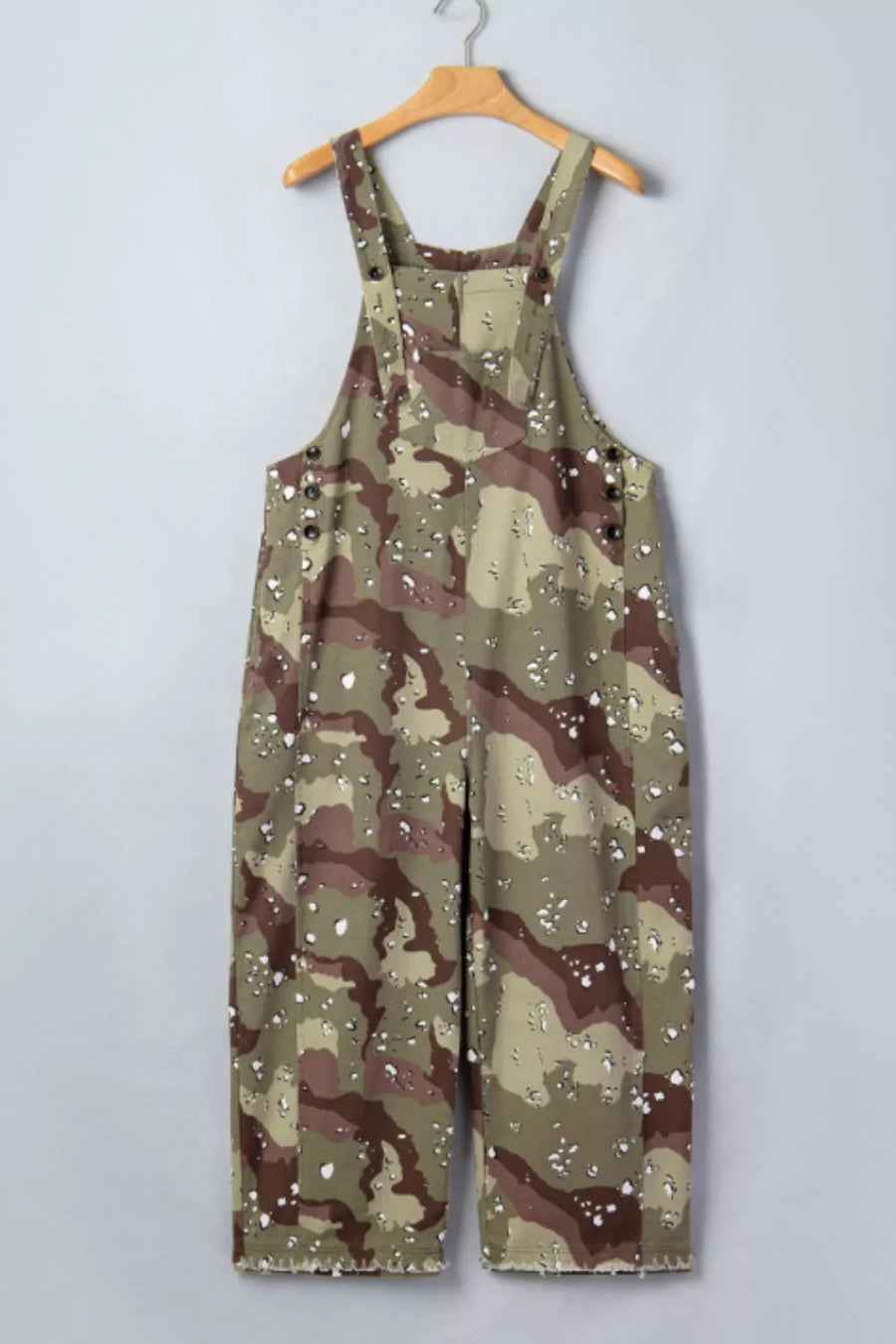 Camouflage overalls on a hanger against a plain background