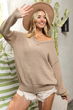Woman wearing a beige sweater and hat, standing in front of a cactus plant.