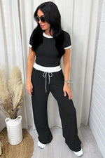 Woman wearing a black and white outfit with sunglasses indoors.