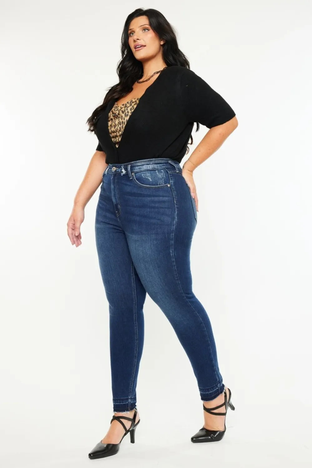 Woman wearing blue jeans and a black top with a leopard print detail on a white background