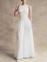 Woman wearing a white dress against a textured beige wall