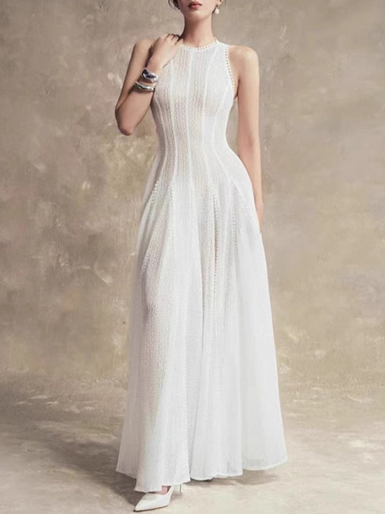 Woman wearing a white dress against a textured beige wall