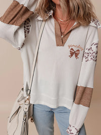 Person wearing a patterned shirt with 'gameday' and a butterfly design, holding a white handbag.