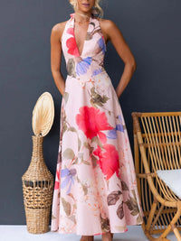 Woman wearing a floral dress standing next to a wicker vase and chair against a dark background