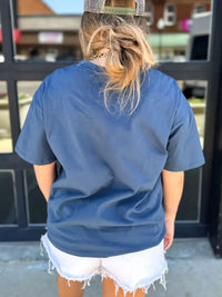 Person wearing a blue t-shirt and white shorts standing in front of a glass door.
