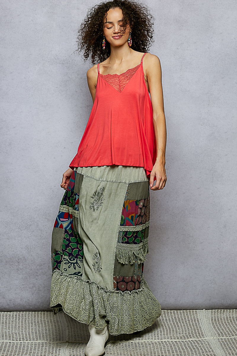 Woman wearing a coral top and patchwork skirt against a gray background