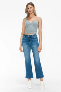 Woman wearing a gray tank top and blue jeans on a white background