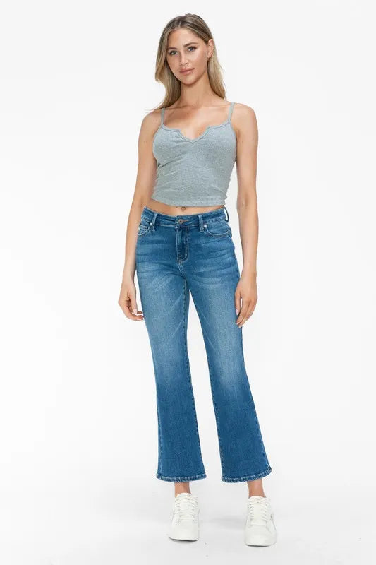 Woman wearing a gray tank top and blue jeans on a white background