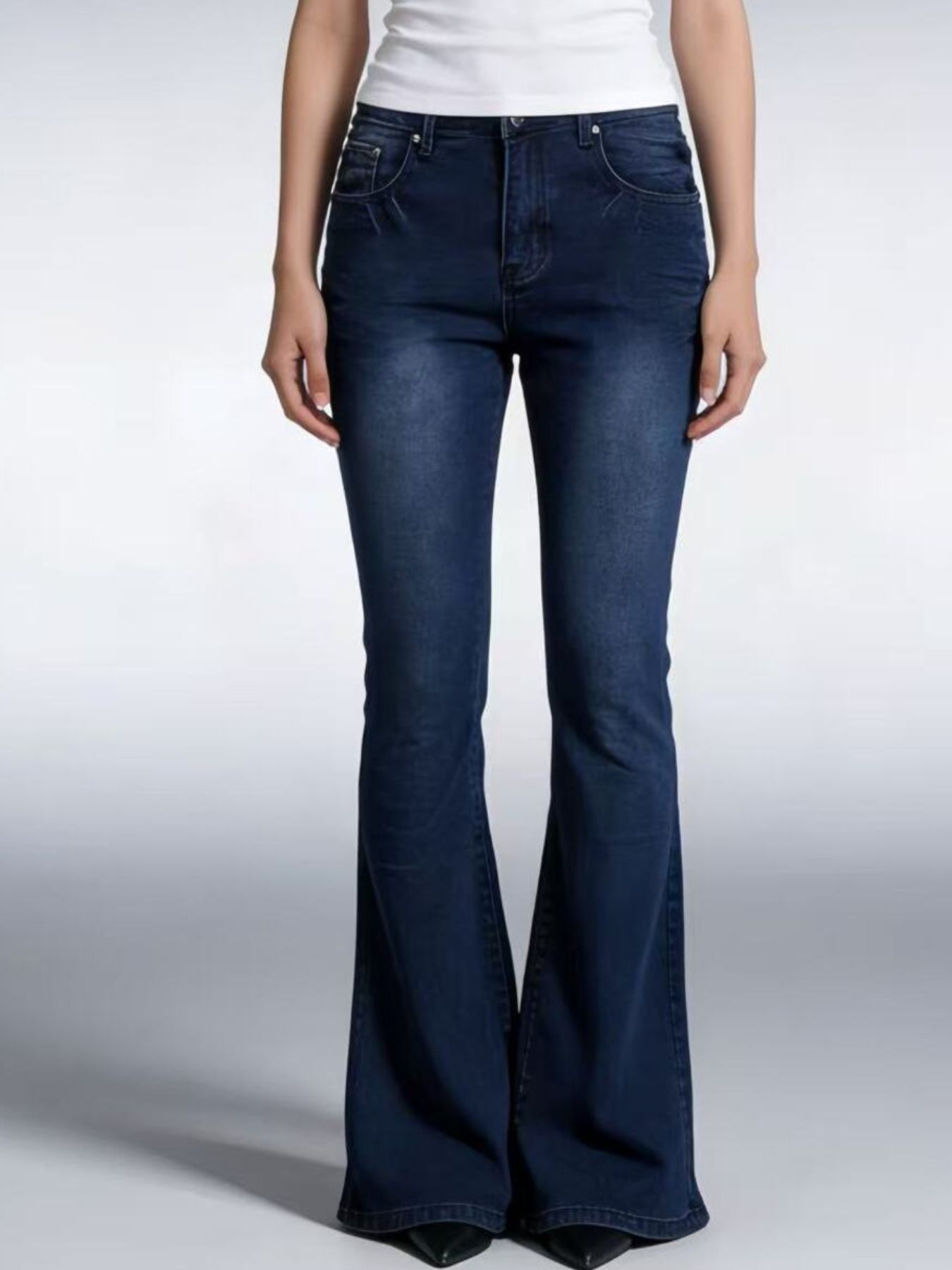 Person wearing dark blue flared jeans on a white background