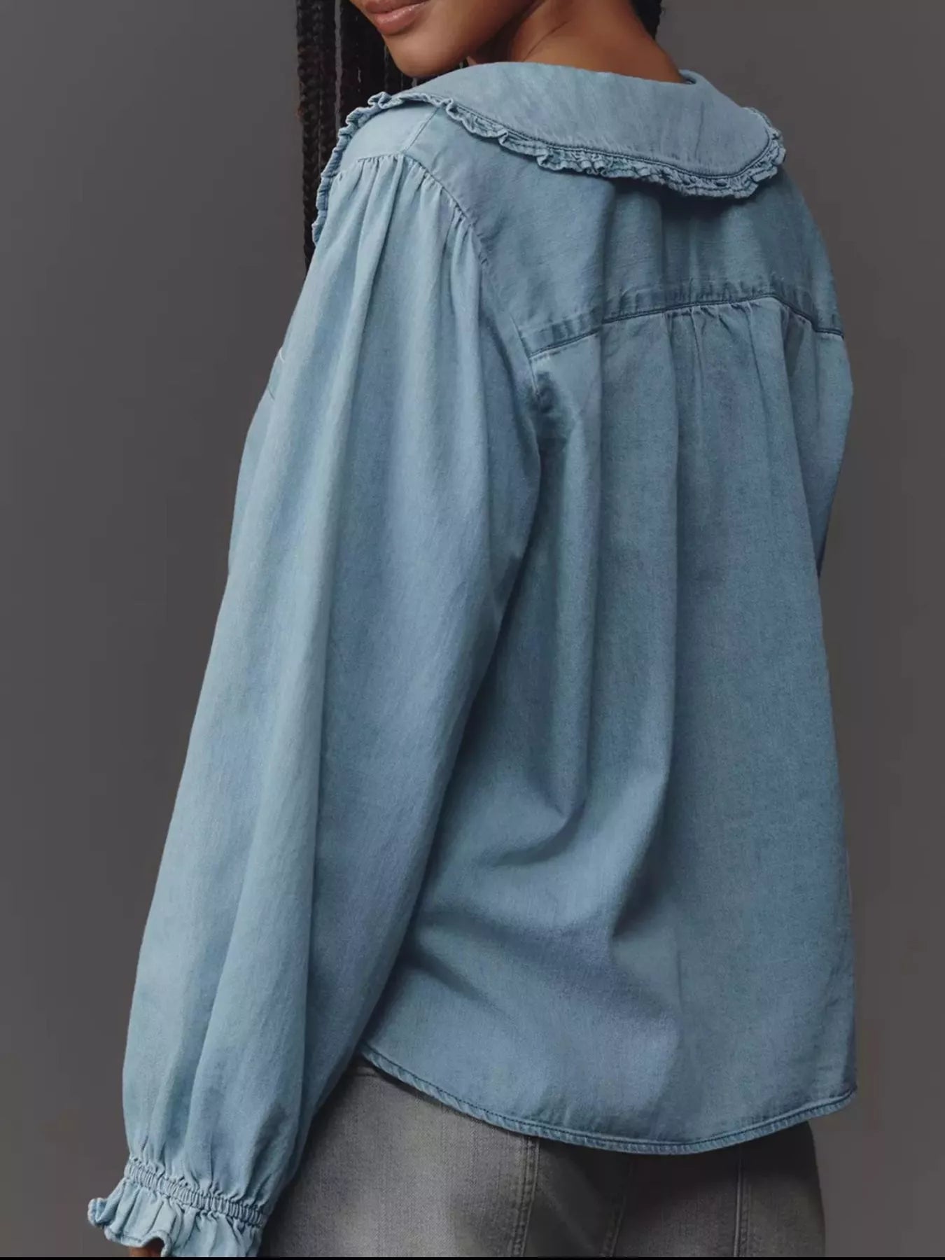 Blue denim shirt with ruffled collar on a gray background