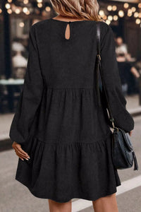 Person wearing a black dress with a blurred indoor background