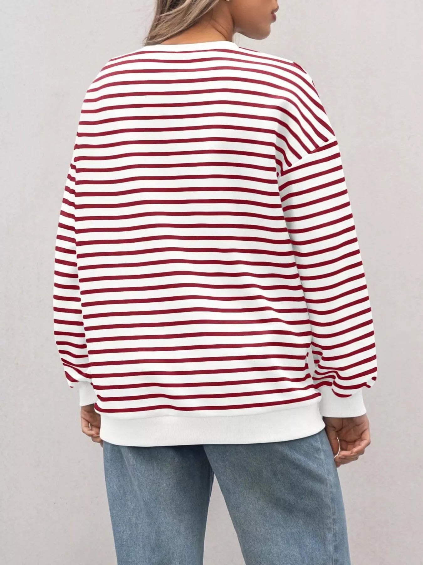 Person wearing a red and white striped sweater with a plain background