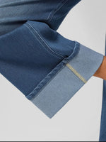 Close-up of a blue denim fabric with a visible brand label on a light gray background