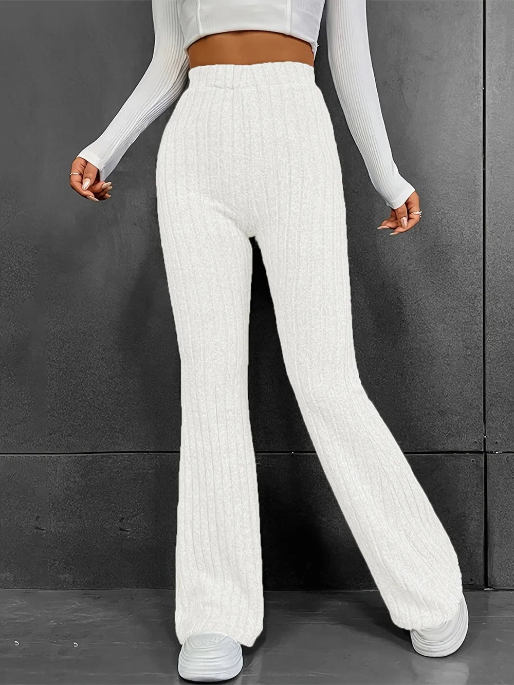 Person wearing white ribbed knit pants against a gray background