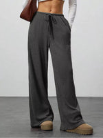 Person wearing gray ribbed knit pants with a plain background