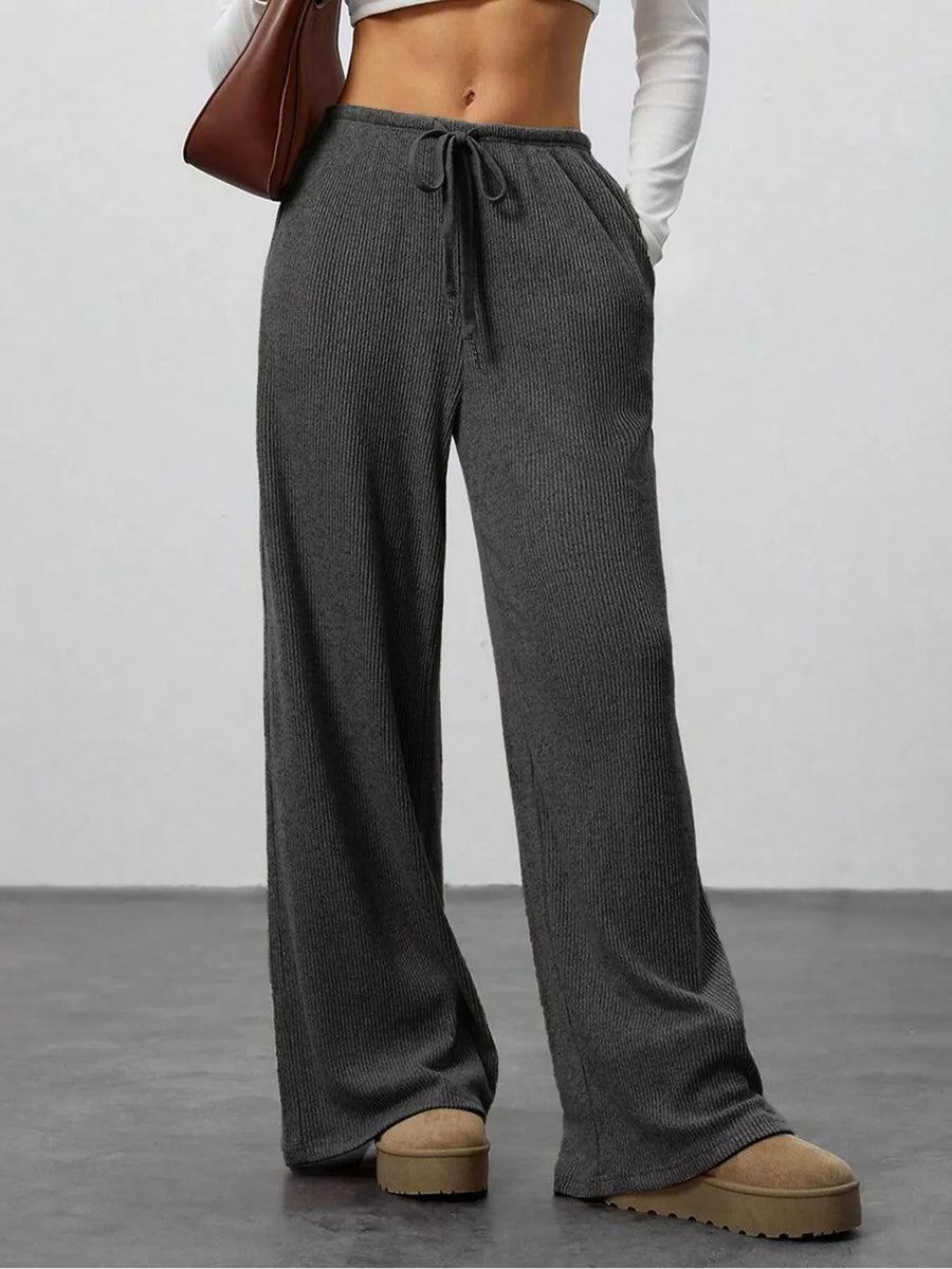Person wearing gray ribbed knit pants with a plain background